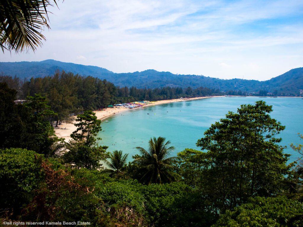 View of Kamala Beach from above, showing clear blue waters and lush greenery