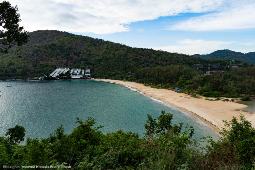 Scenic view of Nai Harn Beach with clear waters and lush green surroundings.