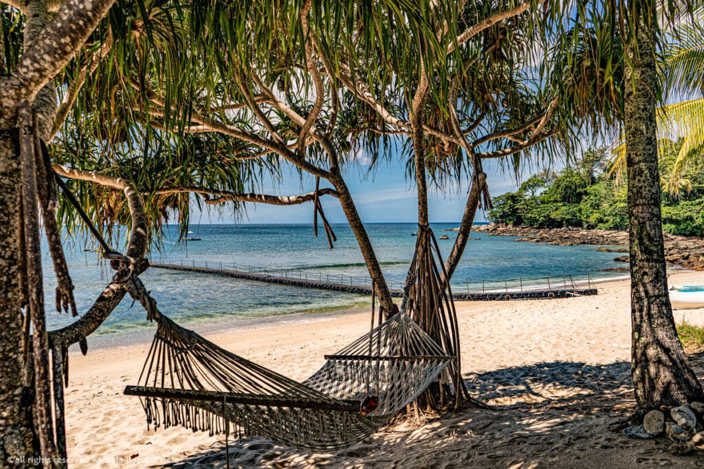 Serene view of Trisara Beach in Phuket with a hammock and pontoon bridge