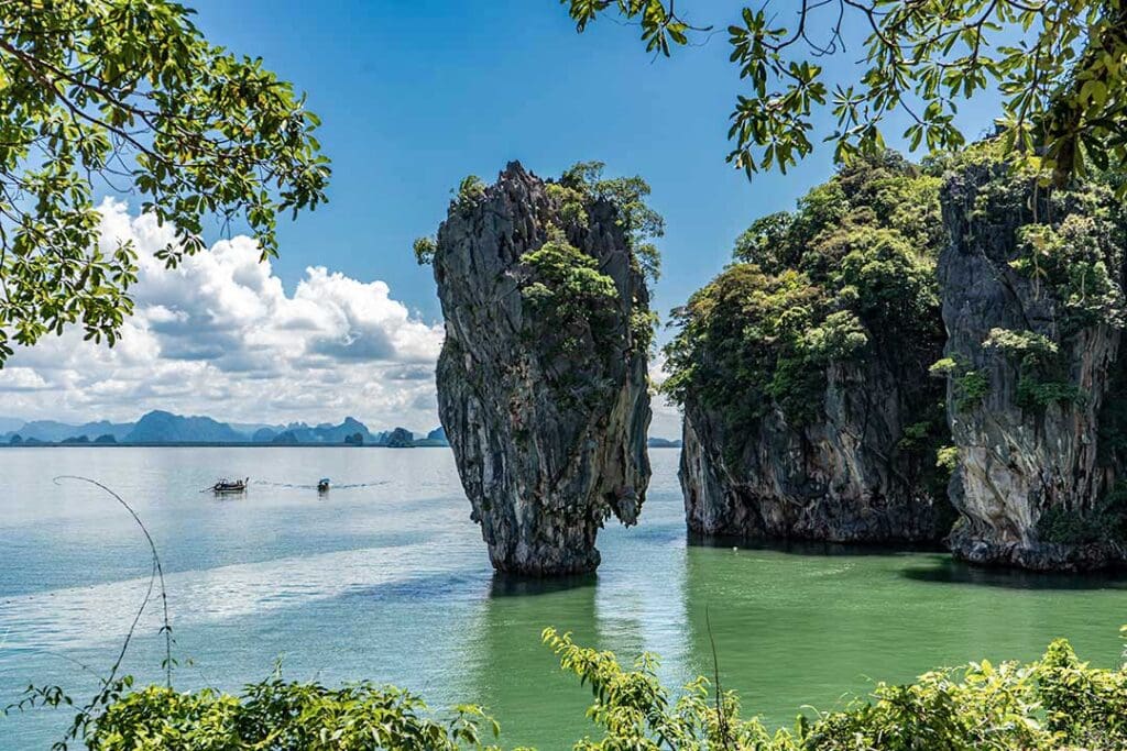 James Bond Island’s Ko Tapu rock formation in Phang Nga Bay, Thailand, with emerald waters and lush foliage in the foreground.