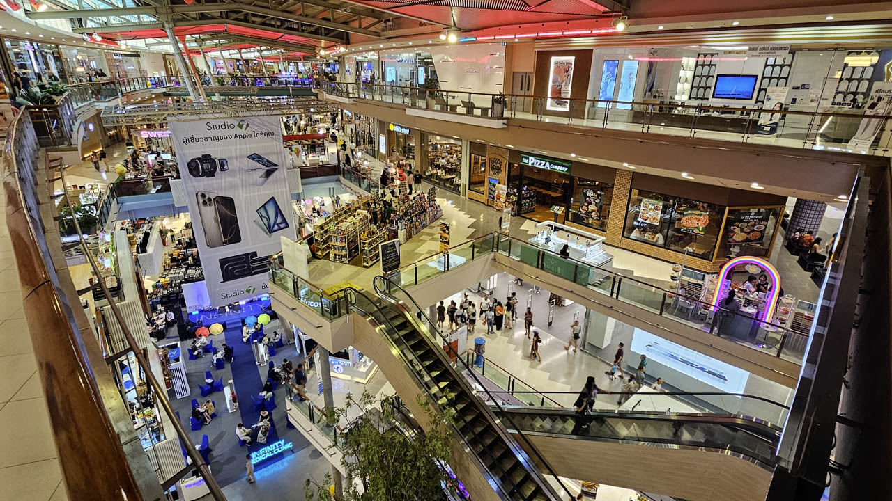 Wide-angle interior of Central Phuket Festival with escalators, fashion outlets, and shoppers