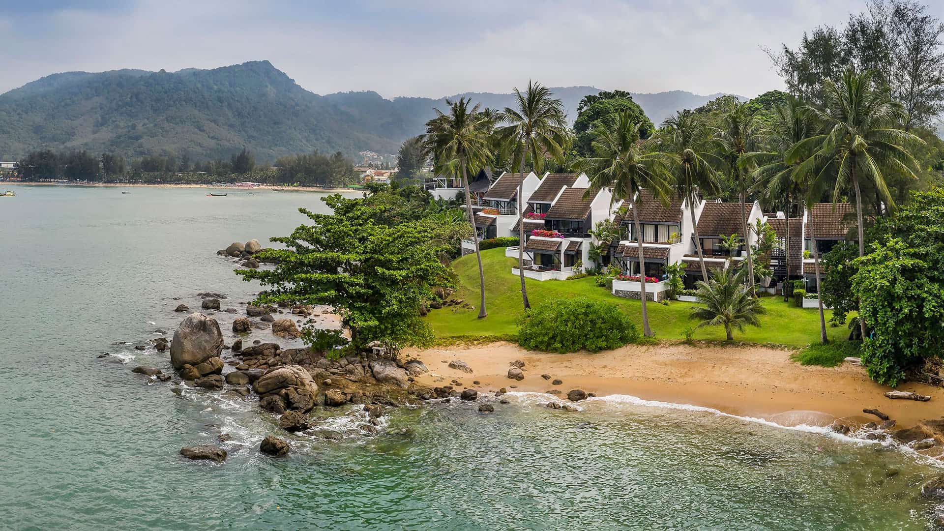 Kamala Beach Estate's buildings, palms and small beach beside the sea